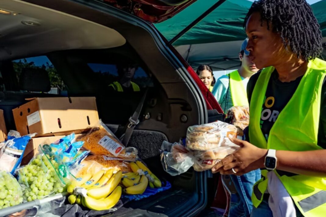 Voluntarios repartiendo cajas de alimentos en un evento de asistencia comunitaria.