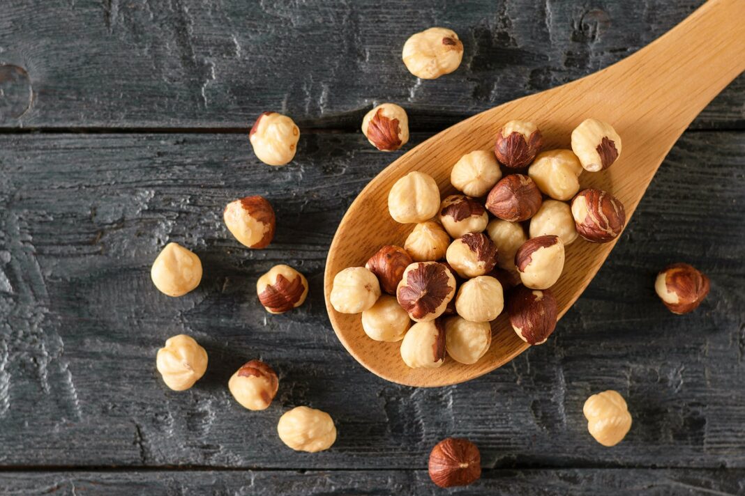 Puñado de avellanas frescas sobre una mesa de madera.