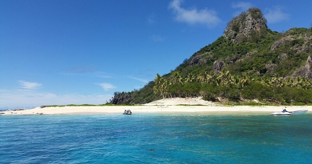 Fotografía aérea del crucero MV Fiji Princess encallado cerca de la costa rocosa de una isla tropical.