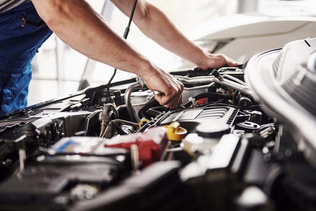 Mecánico trabajando en un automóvil dentro de un taller de reparación.