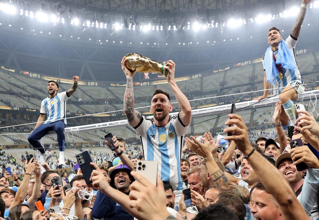 Grupo de personas con camisetas de la selección argentina en una calle, con expresiones expectantes.