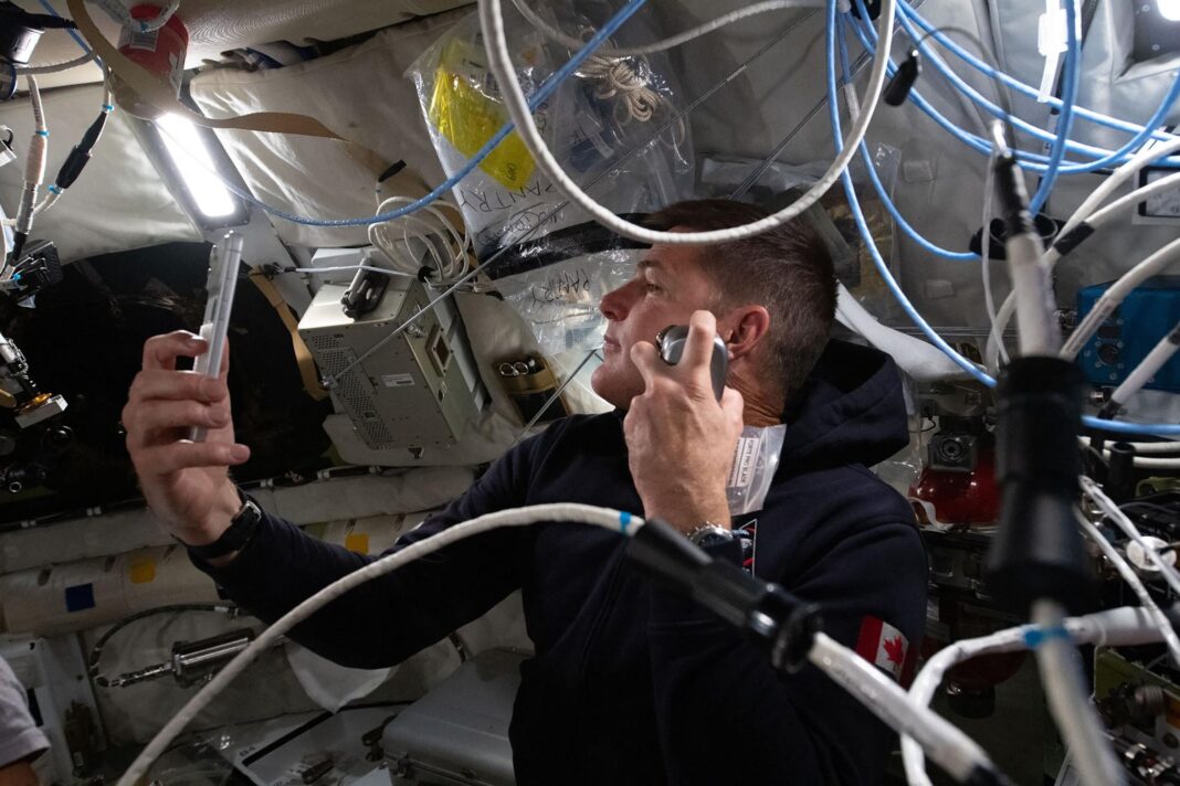 Astronauta de la misión Artemis II sosteniendo un iPhone 17 Pro Max plateado en el interior de la nave espacial.