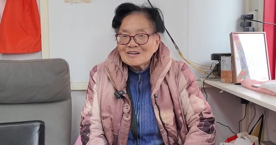 Mujer mayor dentro de una cabina telefónica en la calle Fuzhou, Shanghái