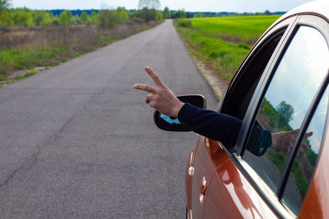 Conductor señalizando con el brazo fuera de la ventanilla de un auto en una calle argentina