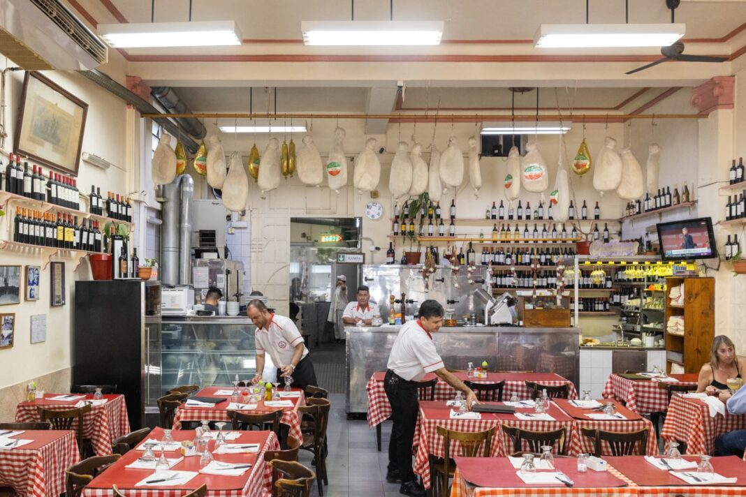 Fachada del restaurante Spiagge di Napoli, con su toldo rojo y puerta de madera, en Buenos Aires.