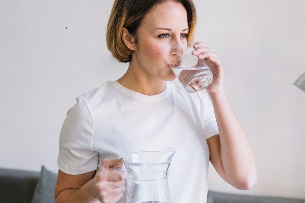 Vaso de agua tibia en una mesa junto a una ventana con luz natural