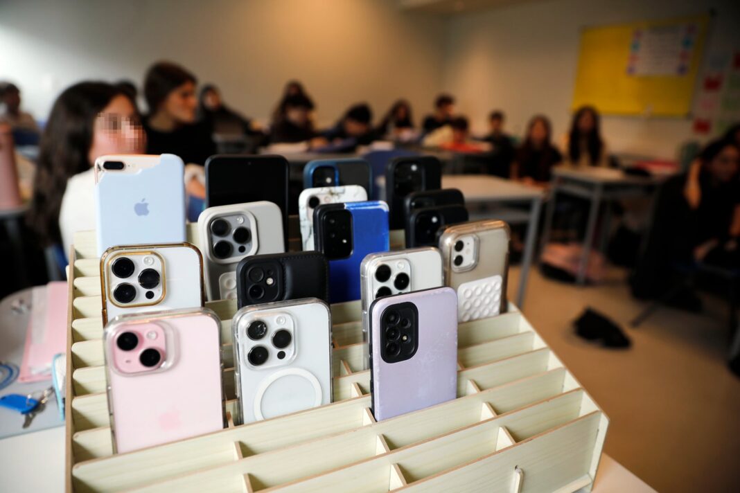 Estudiantes usando celulares en un aula escolar