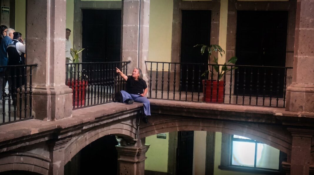 Activista con discapacidad en la cornisa del Palacio de Gobierno de Morelos durante protesta contra aumento del transporte