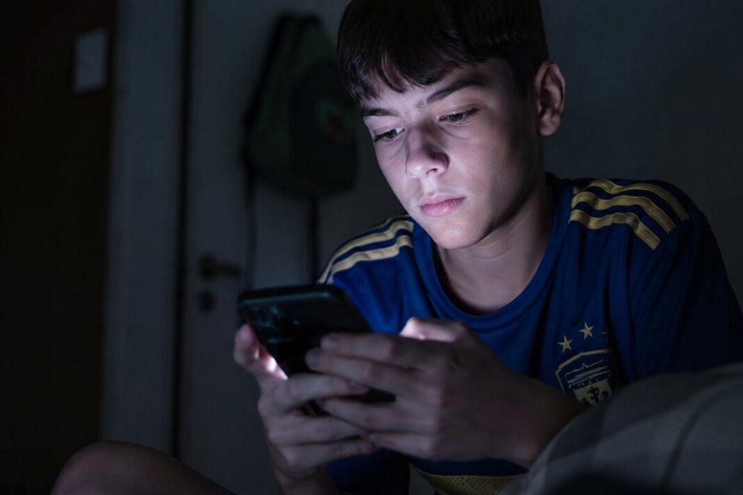 Adolescente usando teléfono celular en contexto de apuestas online