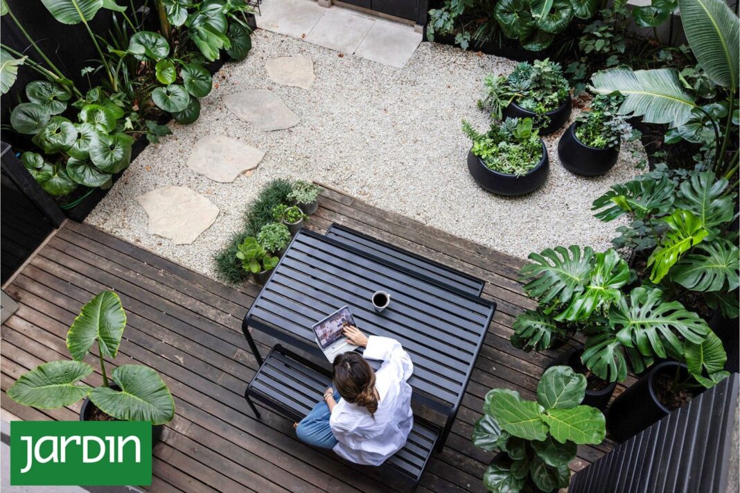 Patio transformado con canteros elevados, sendero de lajas y plantas de hojas grandes