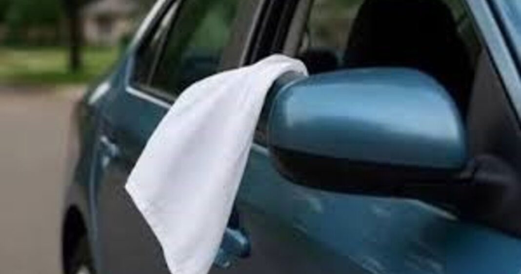 Auto en banquina con tela blanca colgando de la ventana