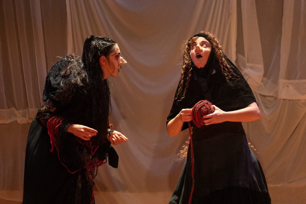 Escena de la obra Bernarda, la de la casa, con actrices en vestuario de clown sobre fondo de telas blancas cosidas