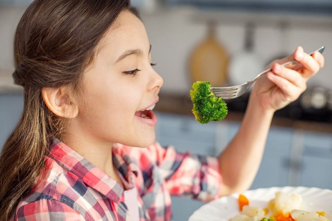 Niños comiendo frutas y verduras en una mesa