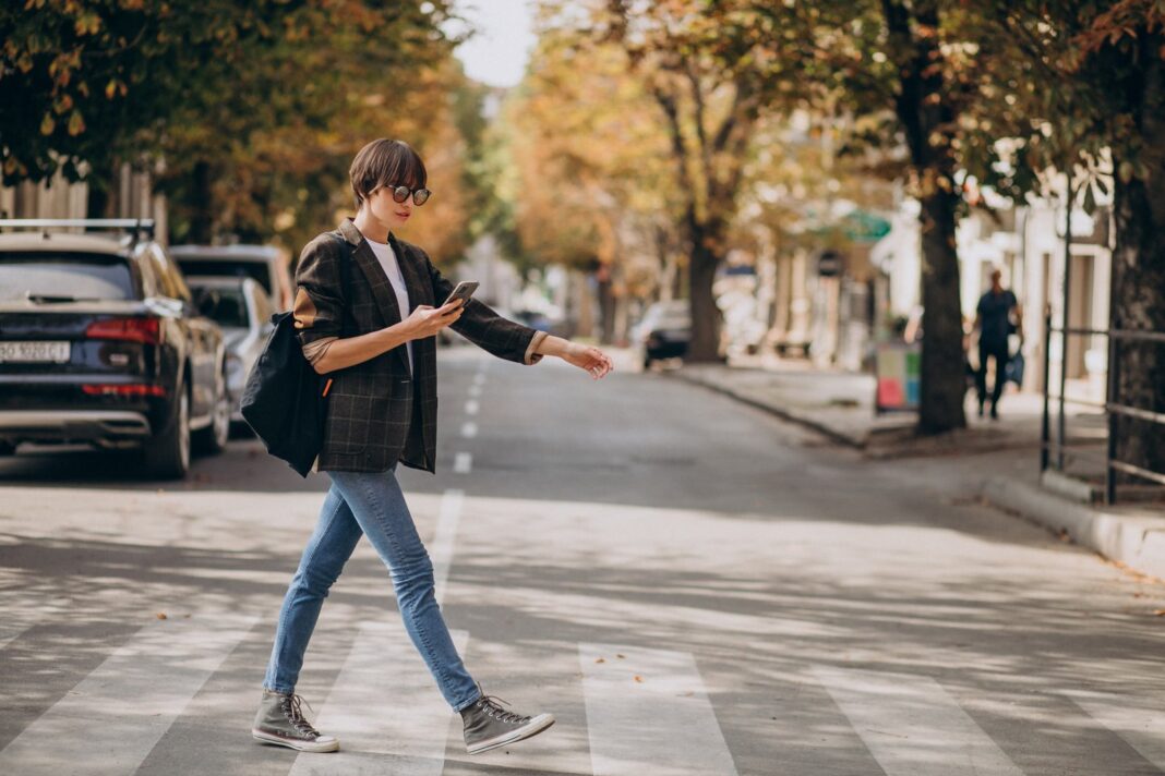 Persona caminando con un teléfono celular en la mano