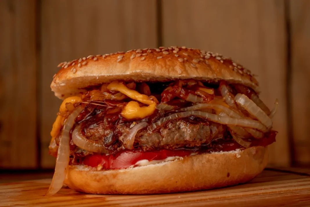 Hamburguesa recién cocida envuelta en papel parafinado sobre una tabla de cocina
