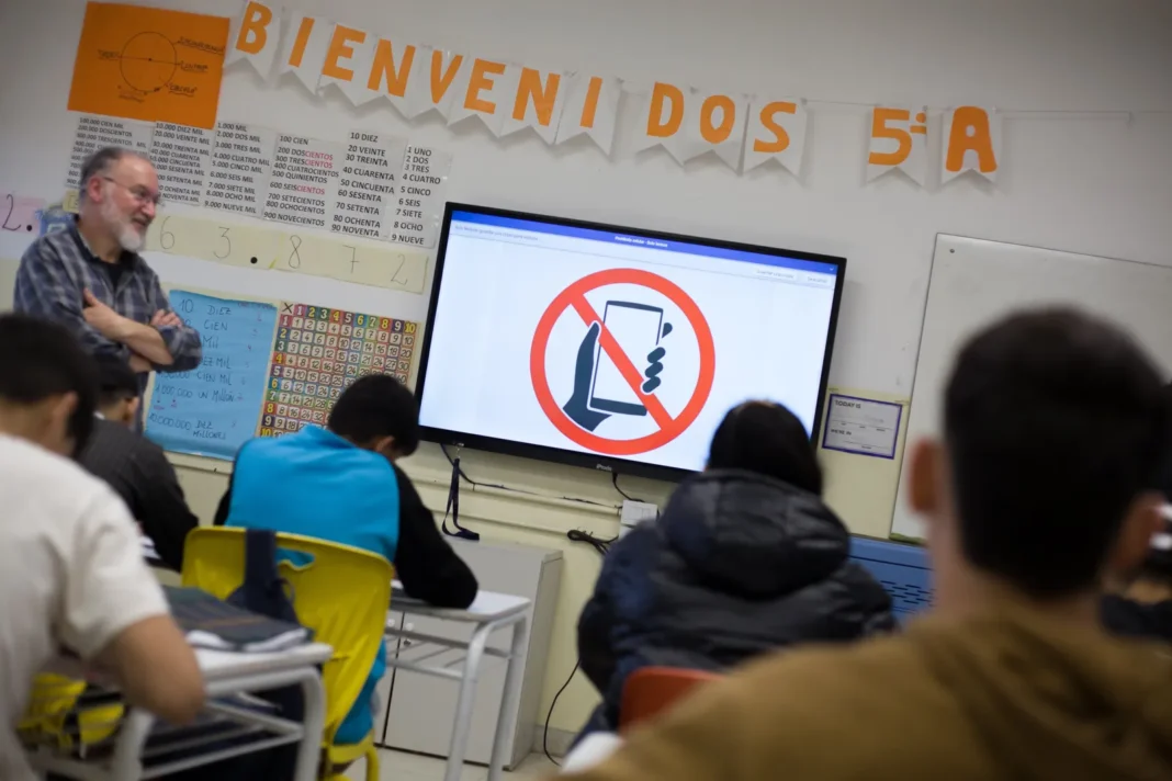 Aula escolar con estudiantes y celulares guardados en mochilas